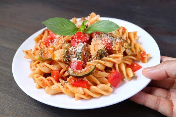 Hand Placing Plate Mouthwatering Wholemeal Fusilli Pasta Tomato Sauce Wooden — Stock Photo, Image