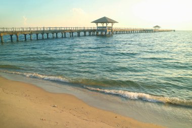 Turkuaz mavi rüzgarlı denizde uzun bir ahşap iskele.