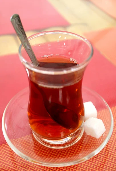 Hot Turkish Tea in Tulip-shaped Glass with Sugar Cubes Isolated on Colorful Luncheon Mats