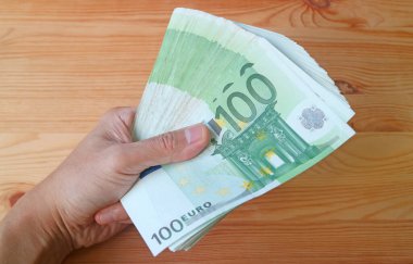 Man 's Hand, ahşap zemin üzerinde 100 Avro Banknota destesi tutuyor