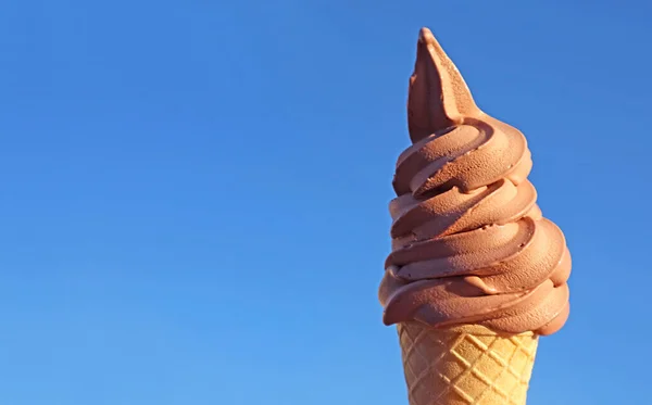 Chocolate Soft Serve Ice Cream Cone Against Vibrant Blue Sunny Sky