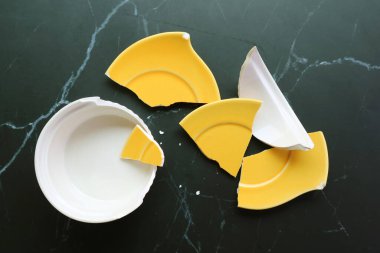 Siyah zemine saçılmış kırık beyaz ve sarı çömlek manzarası