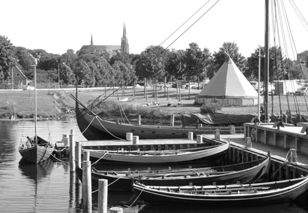 Monochrome Image of Moored Boats at the Viking Ship Museum\'s Pier with St. Luke Cathedral in the Backdrop, Roskilde, Denmark