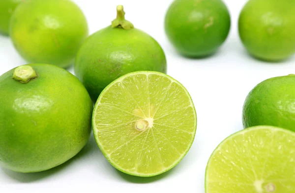 Closeup Fresh Limes Cross Section Whole Fruits Scattered White Backdrop — Foto de Stock