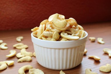 A Bowl Full of Dried Cashew Nuts with Some Kernels Scattered on Wooden Table