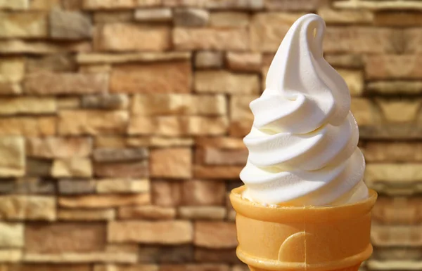 Delectable Vanilla Soft Serve Ice Cream Cone Against Stone Block Wall