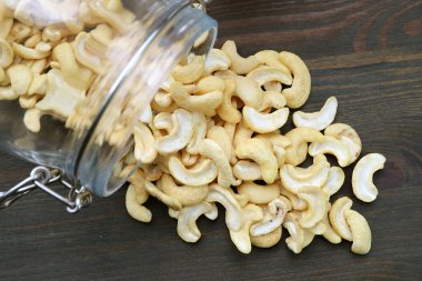 Heap of Casshew Nuts Scattered from a Glass Jar on Wooden Table