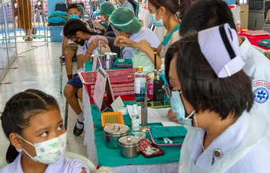 CHIANG MAI, THAILAND - 07 Mart 2022: Bir kız aşı kampanyası sırasında Pfizer-BioNTech COVID-19 aşısını (Comirnaty) aldı. Tayland, Baan Sankamphaeng Okulu 'nda 5-11 yaş arası çocukları aşılıyor..