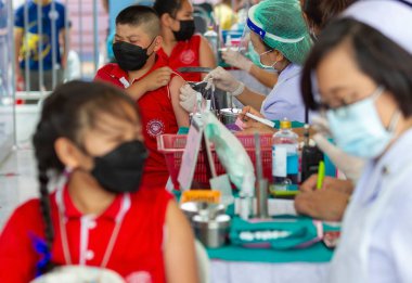 CHIANG MAI, THAILAND - 07 Mart 2022: Bir çocuk (C) aşı kampanyası sırasında Pfizer-BioNTech COVID-19 aşısını (Comirnaty) aldı. Tayland, Baan Sankamphaeng Okulu 'nda 5-11 yaş arası çocukları aşılıyor..