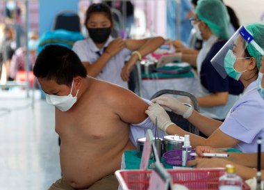 CHIANG MAI, THAILAND - 07 Mart 2022: Bir erkek (F) aşı kampanyası sırasında Pfizer-BioNTech COVID-19 aşısını (Comirnaty) alırken gömleklerini çıkarıyor. Tayland, Baan Sankamphaeng Okulu 'nda çocukları aşılıyor..