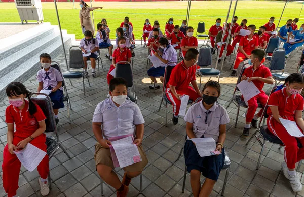 CHIANG MAI, THAILAND - 07 Mart 2022: Yüz maskesi takmış çocuklar Tayland 'ın Chiang Mai kentindeki Baan Sankamphaeng Okulu' nda Pfizer-BioNTech (Comirnaty) Covid-19 aşısı için sıralarını bekliyorlar.
