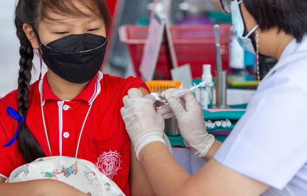 CHIANG MAI, THAILAND - 07 Mart 2022: Bir kız aşı kampanyası sırasında Pfizer-BioNTech COVID-19 aşısını (Comirnaty) aldı. Tayland, Baan Sankamphaeng Okulu 'nda 5-11 yaş arası çocukları aşılıyor..