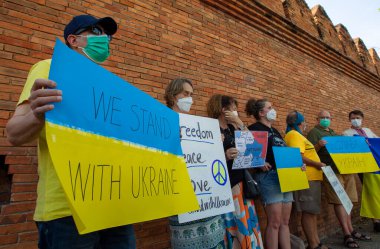 CHIANG MAI, THAILAND - 06 Mart 2022: Eylemciler, Rusya 'nın Tha Phae Kapısı' ndaki Ukrayna işgaline karşı barışçıl bir gösteri sırasında pankart ve Ukrayna bayrakları tutuyorlar