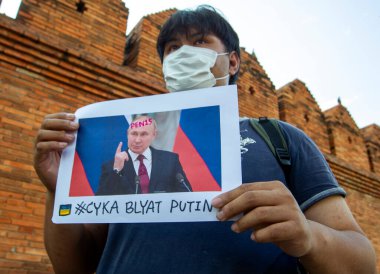 CHIANG MAI, THAILAND - Mart 06 2022: (EDITOR 'un Notu; İMAGE KONUŞMASI PROFANITY) Tayland aktivisti, Rusya' nın Tha Phae Kapısı 'ndaki Ukrayna işgaline karşı barışçıl gösterisinde Rus başkan Vladimir Putin' e karşı bir pankart tutuyor.