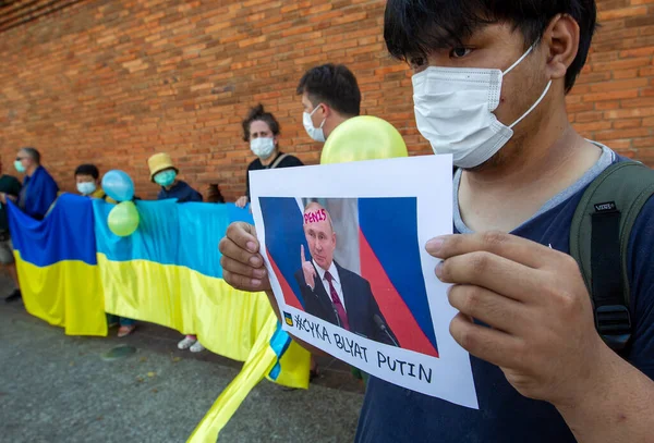 CHIANG MAI, THAILAND - Mart 06 2022: (EDITOR 'un Notu; İMAGE KONTASI PROFANİTESİ) Taylandlı aktivist, Rusya başkanı Vladimir Putin ve Ukrayna' nın Tha Phae Kapısı 'ndaki Rus işgaline karşı yapılan gösteriler sırasında Ukrayna bayraklarına karşı bir pankart tutuyor