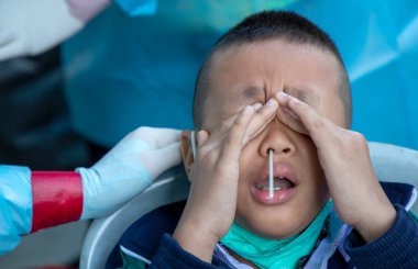 CHIANG MAI, THAILAND - Ban Pamuad Okulu 'nda hızlı bir antijen testi için bir sağlık çalışanı bir öğrenciden burun örneği alır. Tayland 5-11 yaşlarındaki çocukları aşılamaya başladı..