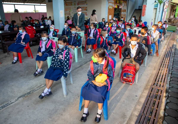 CHIANG MAI, THAILAND - 7 Şubat 2022: Yüz maskesi takan öğrenciler, Ban Pamuad Okulu 'ndaki hızlı bir antijen testi için geniz örneği almayı bekliyor. Tayland 5-11 yaşlarındaki çocukları aşılamaya başladı..
