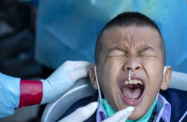 CHIANG MAI, THAILAND - Ban Pamuad Okulu 'nda hızlı bir antijen testi için bir sağlık çalışanı bir öğrenciden burun örneği alır. Tayland 5-11 yaşlarındaki çocukları aşılamaya başladı..
