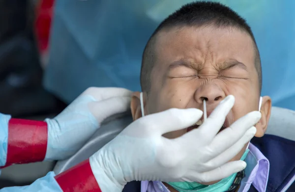 CHIANG MAI, THAILAND - Ban Pamuad Okulu 'nda hızlı bir antijen testi için bir sağlık çalışanı bir öğrenciden burun örneği alır. Tayland 5-11 yaşlarındaki çocukları aşılamaya başladı..