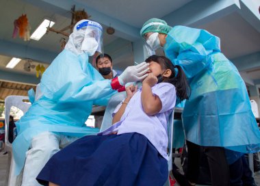 CHIANG MAI, THAILAND - Ban Pamuad Okulu 'nda hızlı bir antijen testi için bir sağlık çalışanı bir öğrenciden burun örneği alır. Tayland 5-11 yaşlarındaki çocukları aşılamaya başladı..