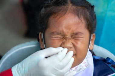 CHIANG MAI, THAILAND - Ban Pamuad Okulu 'nda hızlı bir antijen testi için bir sağlık çalışanı bir öğrenciden burun örneği alır. Tayland 5-11 yaşlarındaki çocukları aşılamaya başladı..