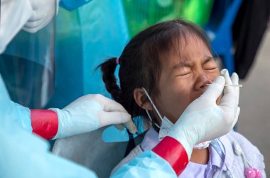 CHIANG MAI, THAILAND - Ban Pamuad Okulu 'nda hızlı bir antijen testi için bir sağlık çalışanı bir öğrenciden burun örneği alır. Tayland 5-11 yaşlarındaki çocukları aşılamaya başladı..
