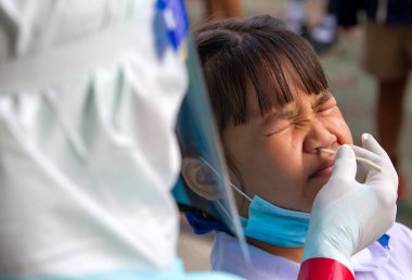 CHIANG MAI, THAILAND - Ban Pamuad Okulu 'nda hızlı bir antijen testi için bir sağlık çalışanı bir öğrenciden burun örneği alır. Tayland 5-11 yaşlarındaki çocukları aşılamaya başladı..