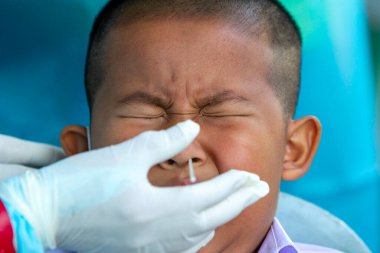 CHIANG MAI, THAILAND - Ban Pamuad Okulu 'nda hızlı bir antijen testi için bir sağlık çalışanı bir öğrenciden burun örneği alır. Tayland 5-11 yaşlarındaki çocukları aşılamaya başladı..