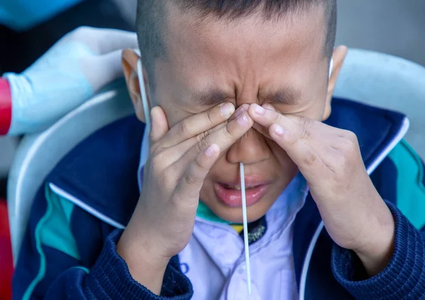 CHIANG MAI, THAILAND - Ban Pamuad Okulu 'nda hızlı bir antijen testi için bir sağlık çalışanı bir öğrenciden burun örneği alır. Tayland 5-11 yaşlarındaki çocukları aşılamaya başladı..