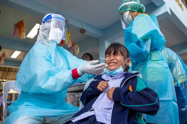 CHIANG MAI, THAILAND - Ban Pamuad Okulu 'nda hızlı bir antijen testi için bir sağlık çalışanı bir öğrenciden burun örneği alır. Tayland 5-11 yaşlarındaki çocukları aşılamaya başladı..