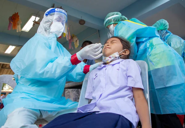 CHIANG MAI, THAILAND - Ban Pamuad Okulu 'nda hızlı bir antijen testi için bir sağlık çalışanı bir öğrenciden burun örneği alır. Tayland 5-11 yaşlarındaki çocukları aşılamaya başladı..