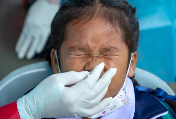 CHIANG MAI, THAILAND - Ban Pamuad Okulu 'nda hızlı bir antijen testi için bir sağlık çalışanı bir öğrenciden burun örneği alır. Tayland 5-11 yaşlarındaki çocukları aşılamaya başladı..