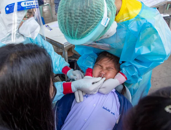 CHIANG MAI, THAILAND - Ban Pamuad Okulu 'nda hızlı bir antijen testi için bir sağlık çalışanı bir öğrenciden burun örneği alır. Tayland 5-11 yaşlarındaki çocukları aşılamaya başladı..