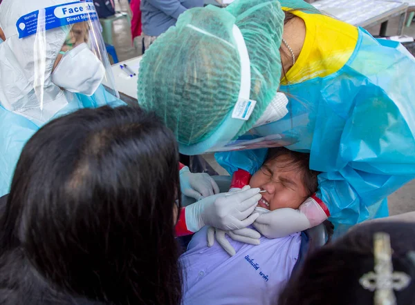 CHIANG MAI, THAILAND - Ban Pamuad Okulu 'nda hızlı bir antijen testi için bir sağlık çalışanı bir öğrenciden burun örneği alır. Tayland 5-11 yaşlarındaki çocukları aşılamaya başladı..