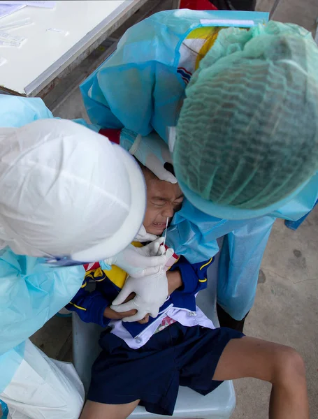 CHIANG MAI, THAILAND - Ban Pamuad Okulu 'nda hızlı bir antijen testi için bir sağlık çalışanı bir öğrenciden burun örneği alır. Tayland 5-11 yaşlarındaki çocukları aşılamaya başladı..