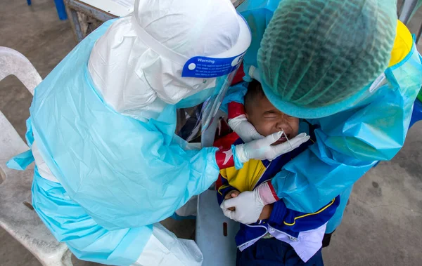 CHIANG MAI, THAILAND - Ban Pamuad Okulu 'nda hızlı bir antijen testi için bir sağlık çalışanı bir öğrenciden burun örneği alır. Tayland 5-11 yaşlarındaki çocukları aşılamaya başladı..