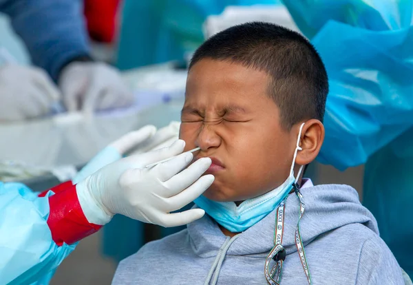 CHIANG MAI, THAILAND - Ban Pamuad Okulu 'nda hızlı bir antijen testi için bir sağlık çalışanı bir öğrenciden burun örneği alır. Tayland 5-11 yaşlarındaki çocukları aşılamaya başladı..