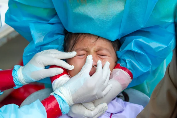 CHIANG MAI, THAILAND - Ban Pamuad Okulu 'nda hızlı bir antijen testi için bir sağlık çalışanı bir öğrenciden burun örneği alır. Tayland 5-11 yaşlarındaki çocukları aşılamaya başladı..