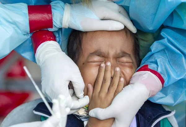 CHIANG MAI, THAILAND - Ban Pamuad Okulu 'nda hızlı bir antijen testi için bir sağlık çalışanı bir öğrenciden burun örneği alır. Tayland 5-11 yaşlarındaki çocukları aşılamaya başladı..