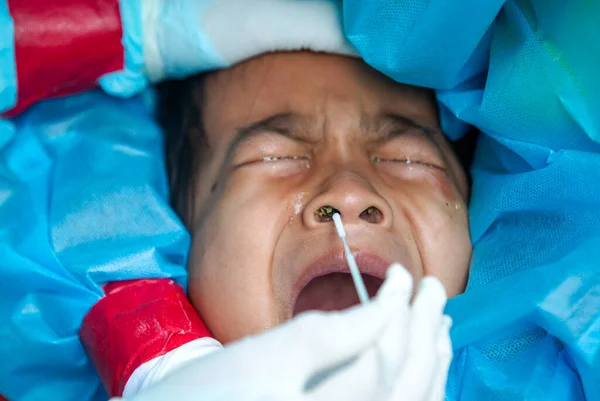 CHIANG MAI, THAILAND - Ban Pamuad Okulu 'nda hızlı bir antijen testi için bir sağlık çalışanı bir öğrenciden burun örneği alır. Tayland 5-11 yaşlarındaki çocukları aşılamaya başladı..