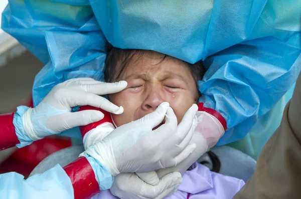 CHIANG MAI, THAILAND - Ban Pamuad Okulu 'nda hızlı bir antijen testi için bir sağlık çalışanı bir öğrenciden burun örneği alır. Tayland 5-11 yaşlarındaki çocukları aşılamaya başladı.. 