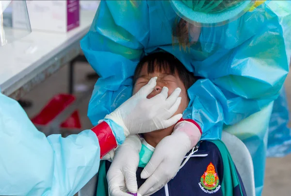 CHIANG MAI, THAILAND - Ban Pamuad Okulu 'nda hızlı bir antijen testi için bir sağlık çalışanı bir öğrenciden burun örneği alır. Tayland 5-11 yaşlarındaki çocukları aşılamaya başladı.. 
