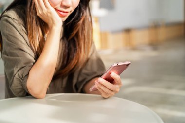 Genç bir kadın akıllı telefon kullanıyor ve kafede dinleniyor, modern yaşam tarzı.