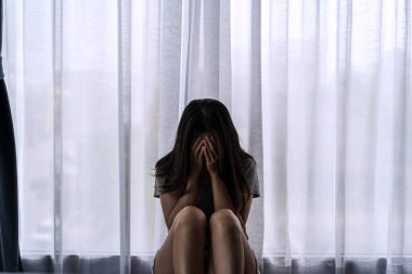 Yalnız genç bir kadın, karanlık bir odada otururken depresyonda ve stresli hissediyor, negatif duygular ve akıl sağlığı kavramı.