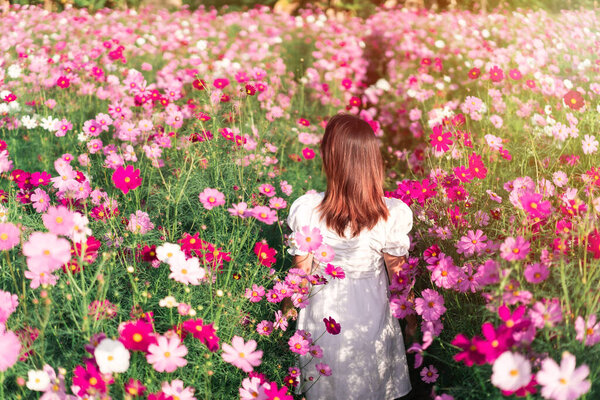 Young woman relaxing and enjoying in blooming flowers field in the morning