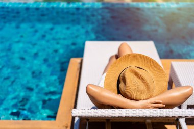 Young woman traveler relaxing at the resort pool while traveling for summer vacation