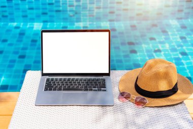 Tropik tatil beldesinde seyahat aksesuarları olan boş ekran dizüstü bilgisayar, yaz tatili konsepti