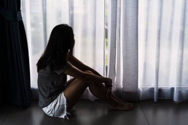 Yalnız genç bir kadın, karanlık bir odada otururken depresyonda ve stresli hissediyor, negatif duygular ve akıl sağlığı kavramı.