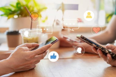 Bir grup arkadaş kafedeki akıllı telefonlardan sosyal medyayı kontrol ediyor.