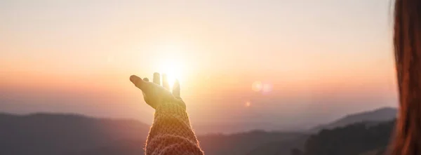 stock image Young woman hand reaching for the mountains during sunset and beautiful landscape